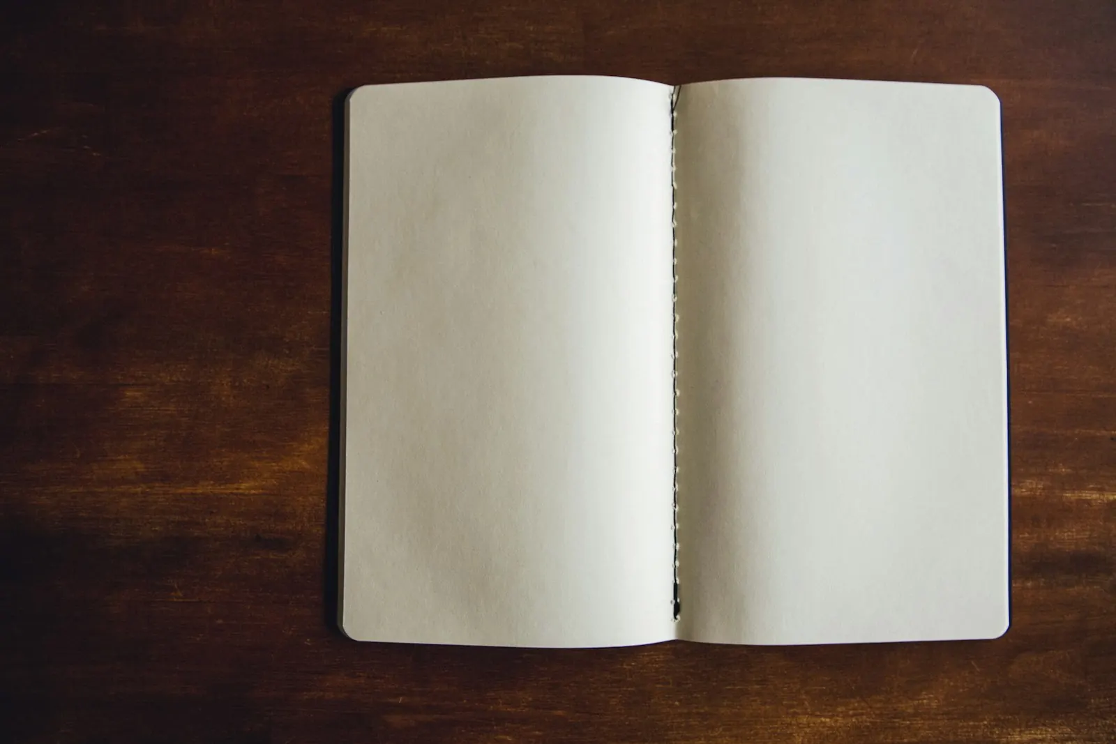 An open blank notebook on a wooden table.
